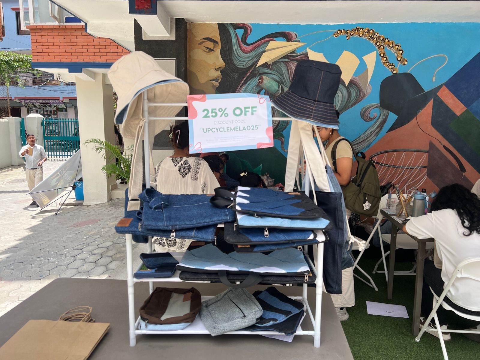 A display rack with denim bags and hats offering a 25% discount at the Upcycle Mela 2025.